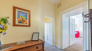 Un pasillo con un aparador de madera, un cuadro enmarco y una puerta que da a otra habitación.
