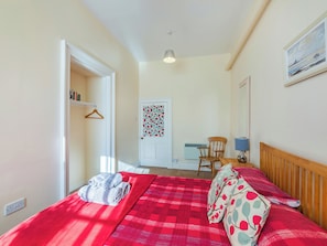 A bedroom with a bed, a chair, a desk, and a door with a floral pattern.