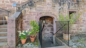 Un edificio de piedra con un letrero que dice 'Hayloft', una pequeña escalera y plantas en macetas.