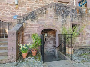 Un edificio in pietra con un'insegna che recita 'Hayloft', una piccola scala e piante in vaso.