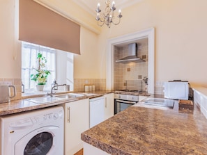 A modern kitchen with a washing machine, oven, and microwave.