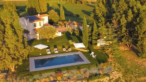 A residential property with a swimming pool, a patio with lounge chairs, and a view of the surrounding countryside. - Casale Rondinella 6+2, Emma Villas (Manciano)