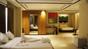 Una habitación de hotel con una cama grande, un armario, una mesita de noche, un espejo y una obra de arte colorida en la pared.