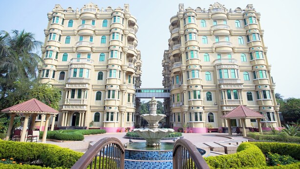Un hotel grande y ornamentado con múltiples balcones y una fuente central.