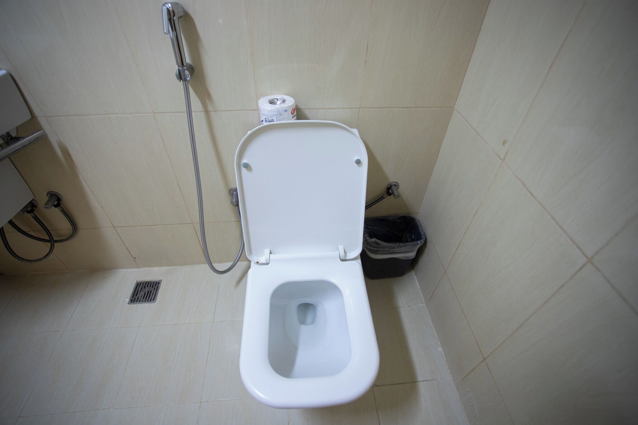 Een standaard badkamer met een wit toilet, een douche en een prullenbak.