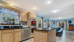 Una cocina amplia con armarios de madera, una isla central y un comedor con una mesa grande.