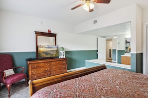 Quarto com cama, cômoda, cadeira e ventilador de teto.