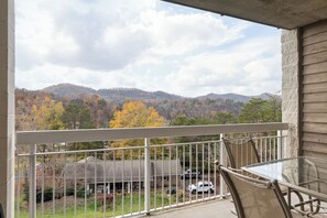 A balcony with a view of a mountain range and autumn foliage.