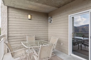 A covered patio with a glass table and chairs, a light fixture, and a view of the outdoors. - 2 Bedroom, Indoor Pool, King Beds, Downtown (Pigeon Forge)