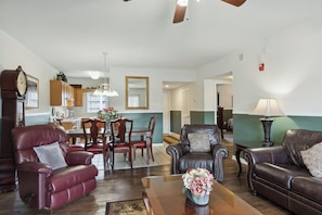 A living room with leather sofas, a dining table with chairs, a kitchen area, and a hallway leading to another room. - 2 Bedroom, Indoor Pool, King Beds, Downtown (Pigeon Forge)