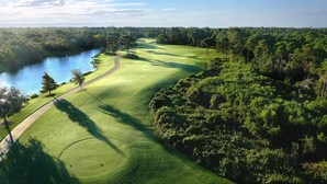 Un campo de golf con un cuerpo de agua, árboles y un cielo despejado.