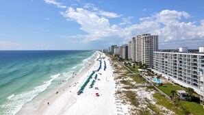 Un hotel frente a la playa con una extensa orilla, vista al océano y varias construcciones.