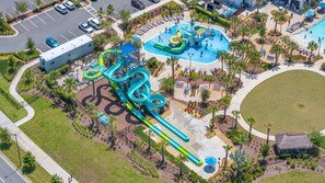 An aerial view of a water park with multiple slides and pools, surrounded by landscaped areas and a parking lot. - 1010 SS - Modern Comfort Oasis (Four Corners)