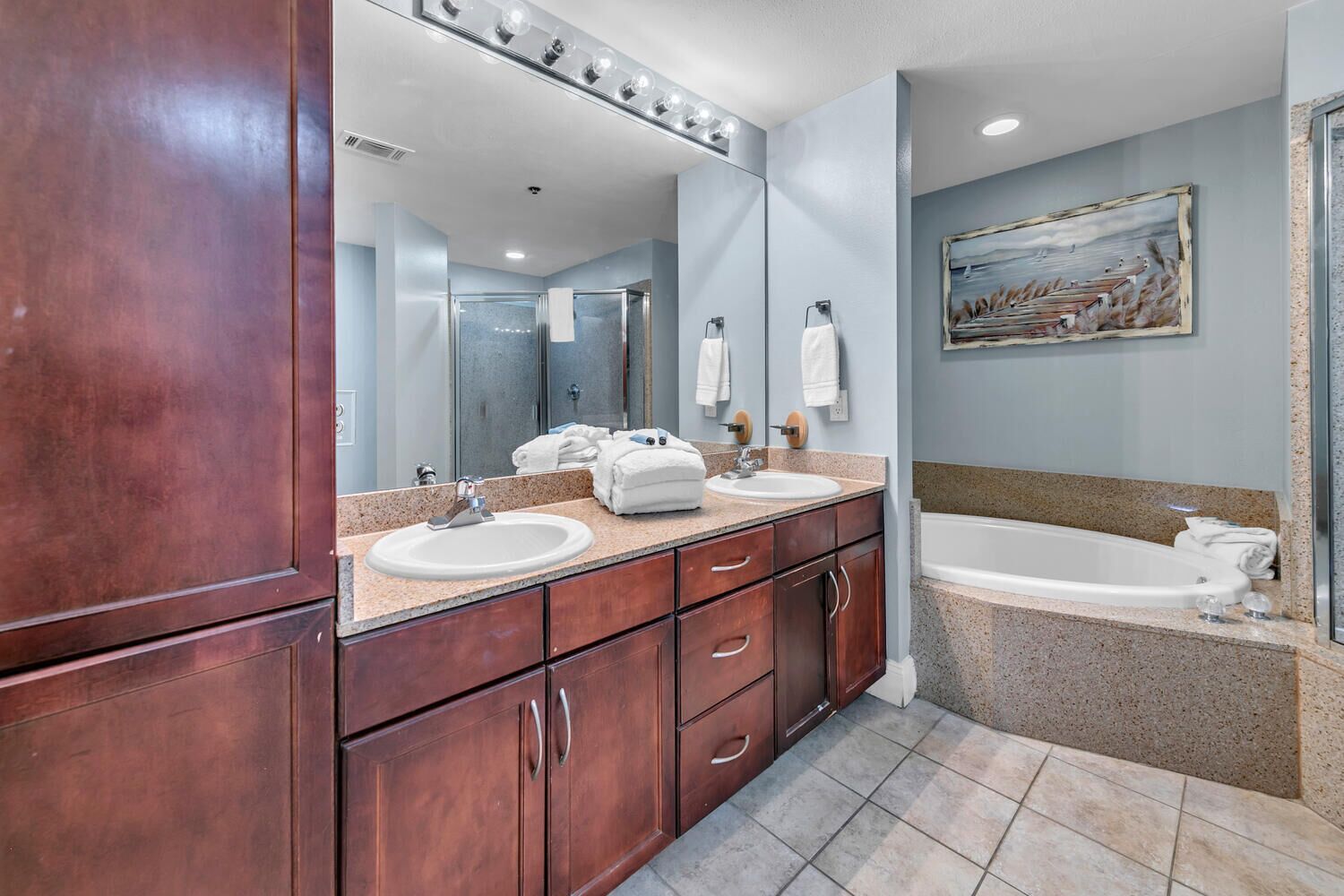 A modern bathroom with a double sink vanity, a large mirror, and a bathtub.
