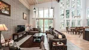 Un salón amplio con chimenea, televisor y comedor con mobiliario de madera.