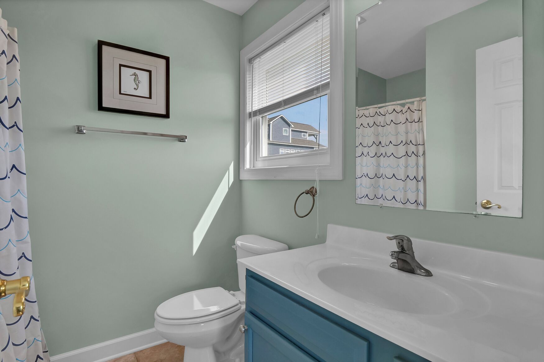 A bathroom with a toilet, sink, and window.
