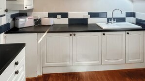 A kitchen with white cabinets, a black countertop, and a wooden floor.