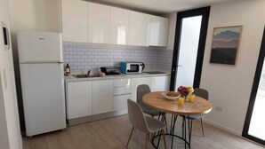 Una cocina moderna con armarios blancos, microondas integrado y un comedor con mesa y sillas redondas.