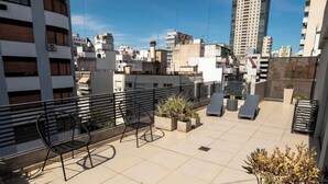 Terraza en la azotea con mobiliario exterior, plantas en macetas y vistas panorámicas de la ciudad.