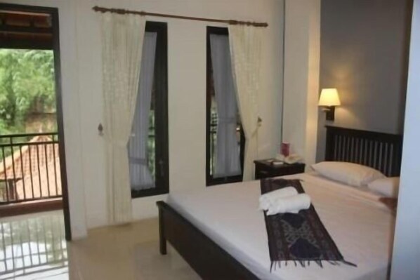 A bedroom with a bed, curtains, a nightstand, and a lamp.