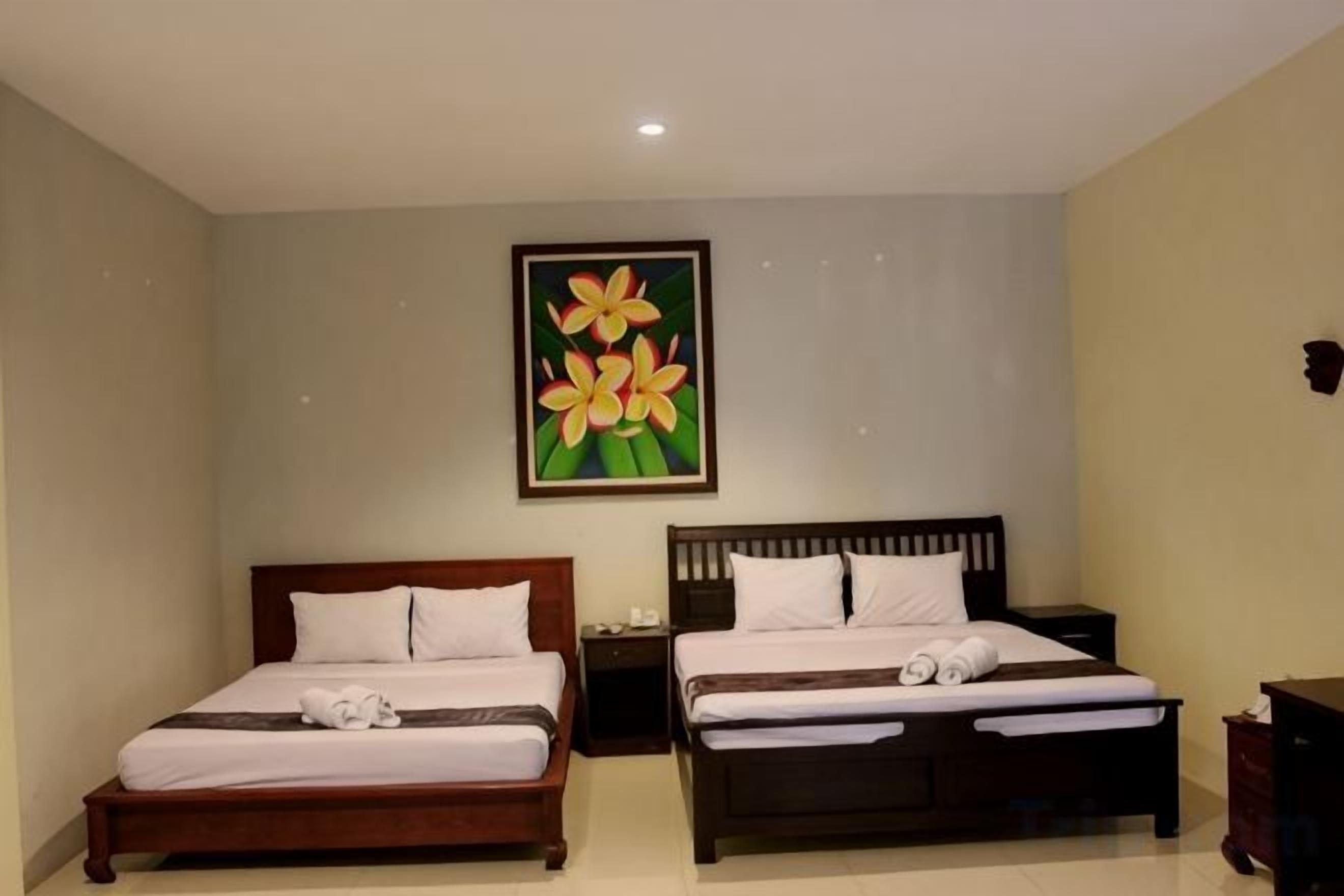 A hotel room with two beds, a nightstand, a dresser, and a painting of flowers on the wall.