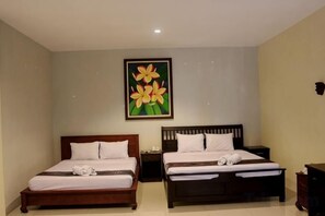 A hotel room with two beds, a nightstand, a dresser, and a painting of flowers on the wall. - Ubud Hotel & Cottages (Sukun)