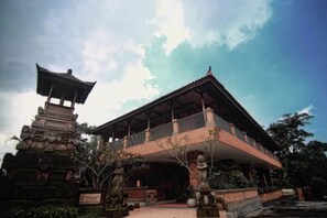 A traditional building with a covered balcony and a pagoda-style structure in front. - Ubud Hotel & Cottages (Sukun)