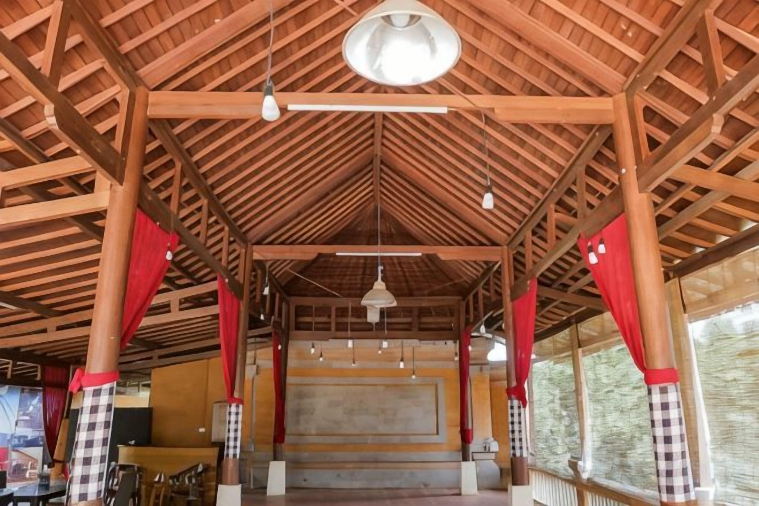 An indoor space with a high ceiling, wooden beams, and red curtains.