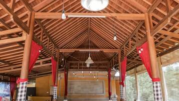 An indoor space with a high ceiling, wooden beams, and red curtains.
