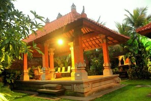 A traditional pavilion with a tiled roof, surrounded by lush greenery. - Ubud Hotel & Cottages (Sukun)