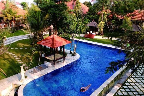 A swimming pool with a gazebo, surrounded by lush greenery and a tiled deck. - Ubud Hotel & Cottages (Sukun)