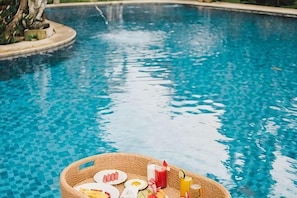 A pool with a wicker tray containing plates, a drink, and a glass. - Ubud Hotel & Cottages (Sukun)
