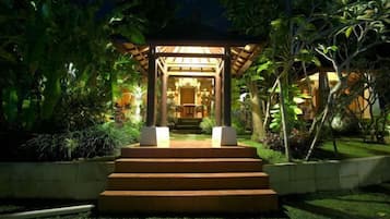 A gazebo with steps leading to it, surrounded by greenery.