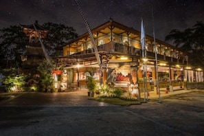 A hotel with a balcony, a signboard, and a well-lit entrance. - Ubud Hotel & Cottages (Sukun)