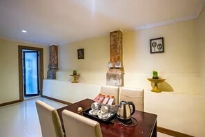 A dining area with a table set for two, a coffee pot, and a tray with food items. - Ubud Hotel & Cottages (Sukun)