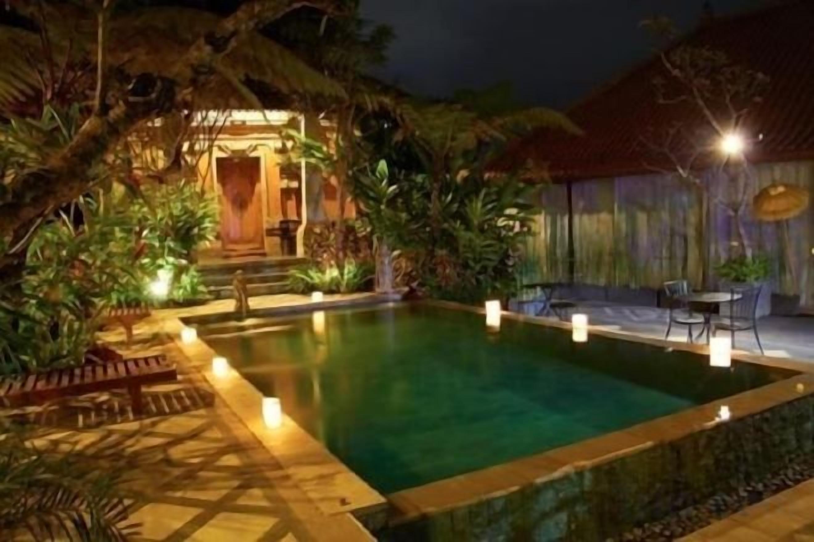 A swimming pool with a surrounding deck and lounge area, surrounded by tropical vegetation.