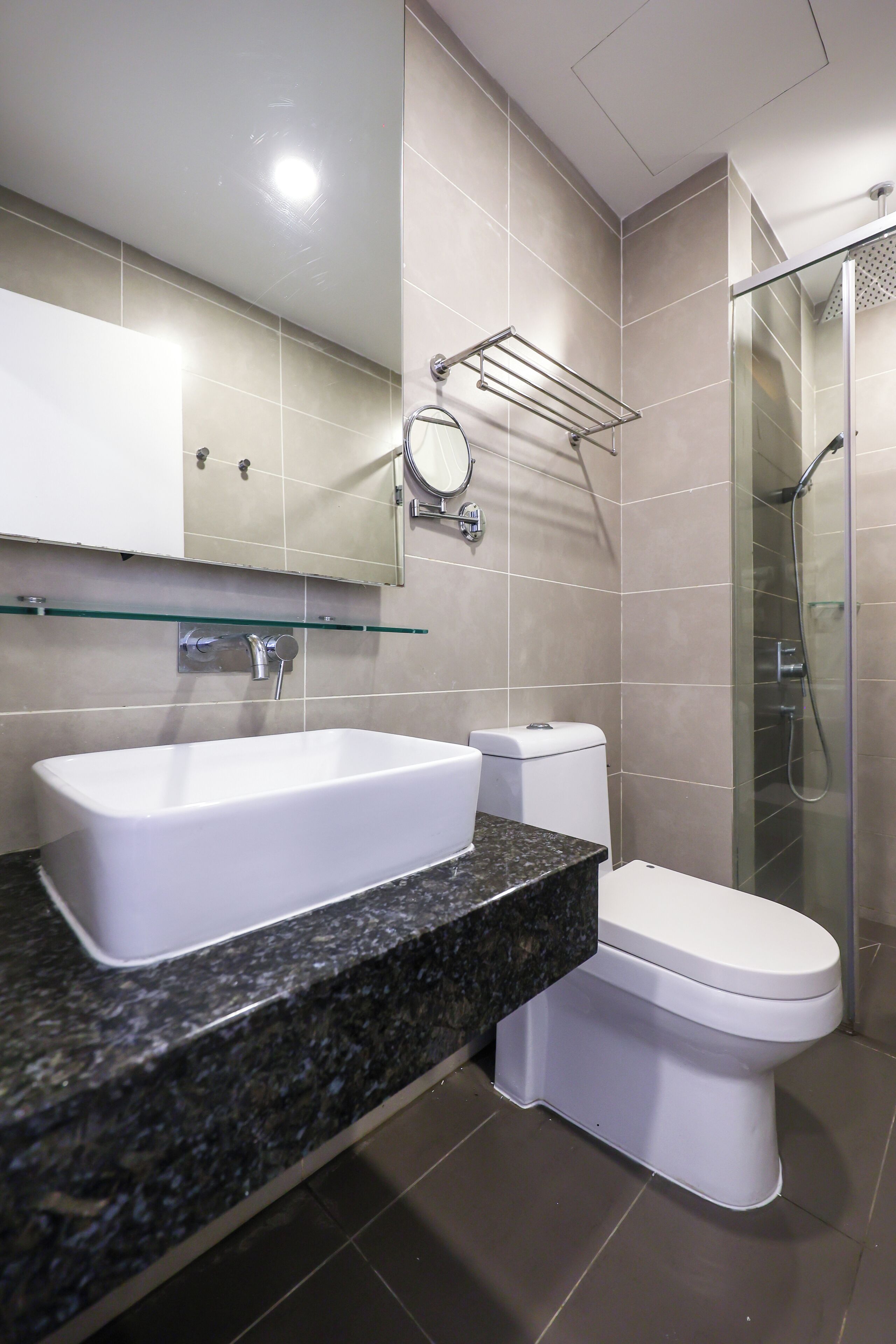 A modern bathroom with a rectangular sink, a toilet, a glass shower enclosure, and a mirror above the sink.