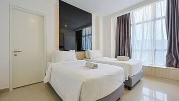 A hotel room with two beds, a large window with curtains, and a door.