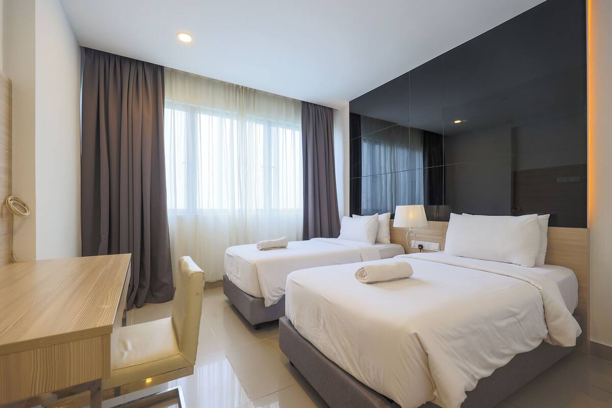 A hotel room with two beds, a desk, and a chair.