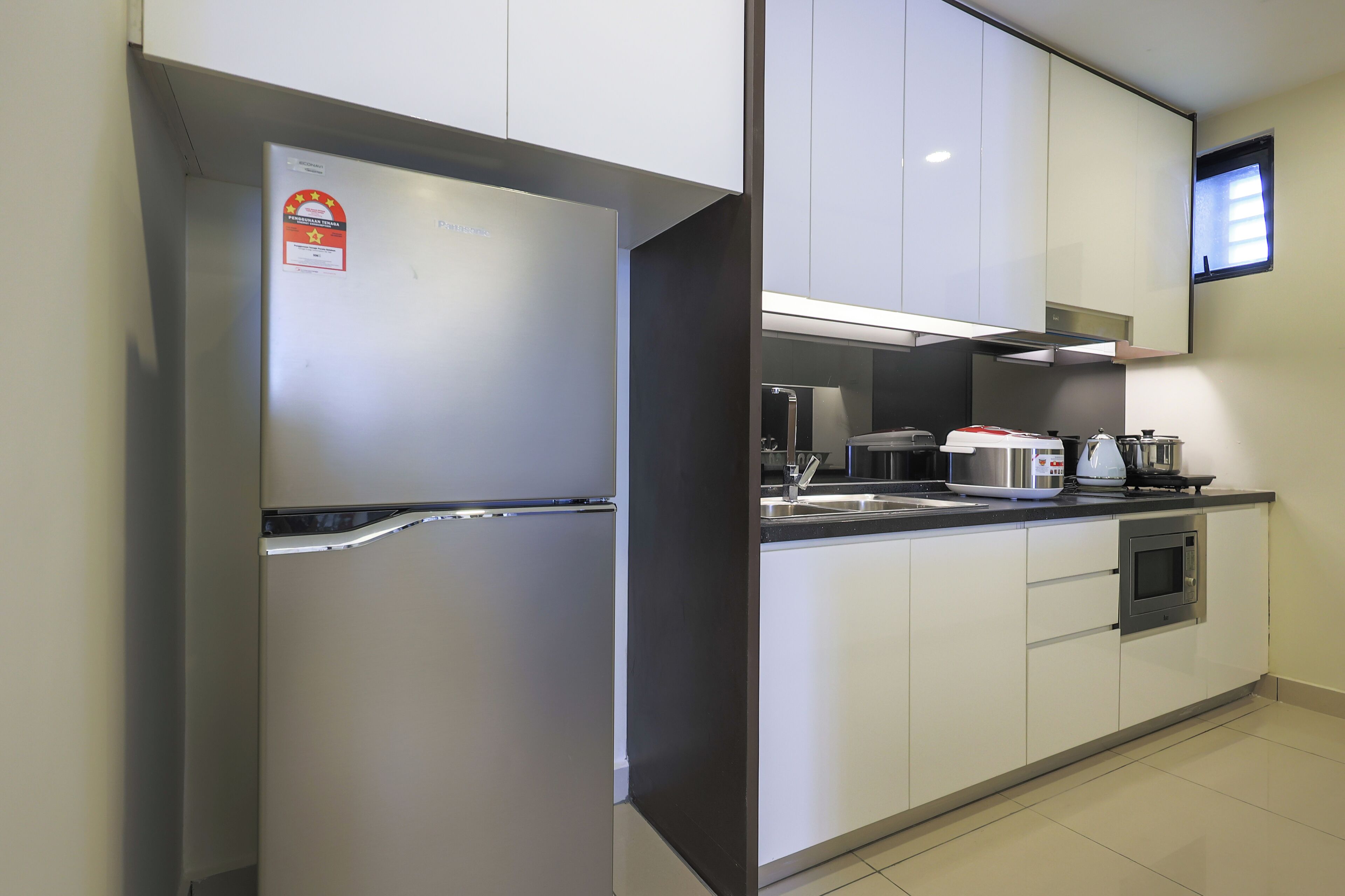 A modern kitchen with stainless steel appliances, white cabinets, and a built-in microwave.