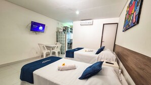 A hotel room with two beds, a TV, a desk, and a bathroom. - Pousada Cheiro do Mar (Ipojuca)