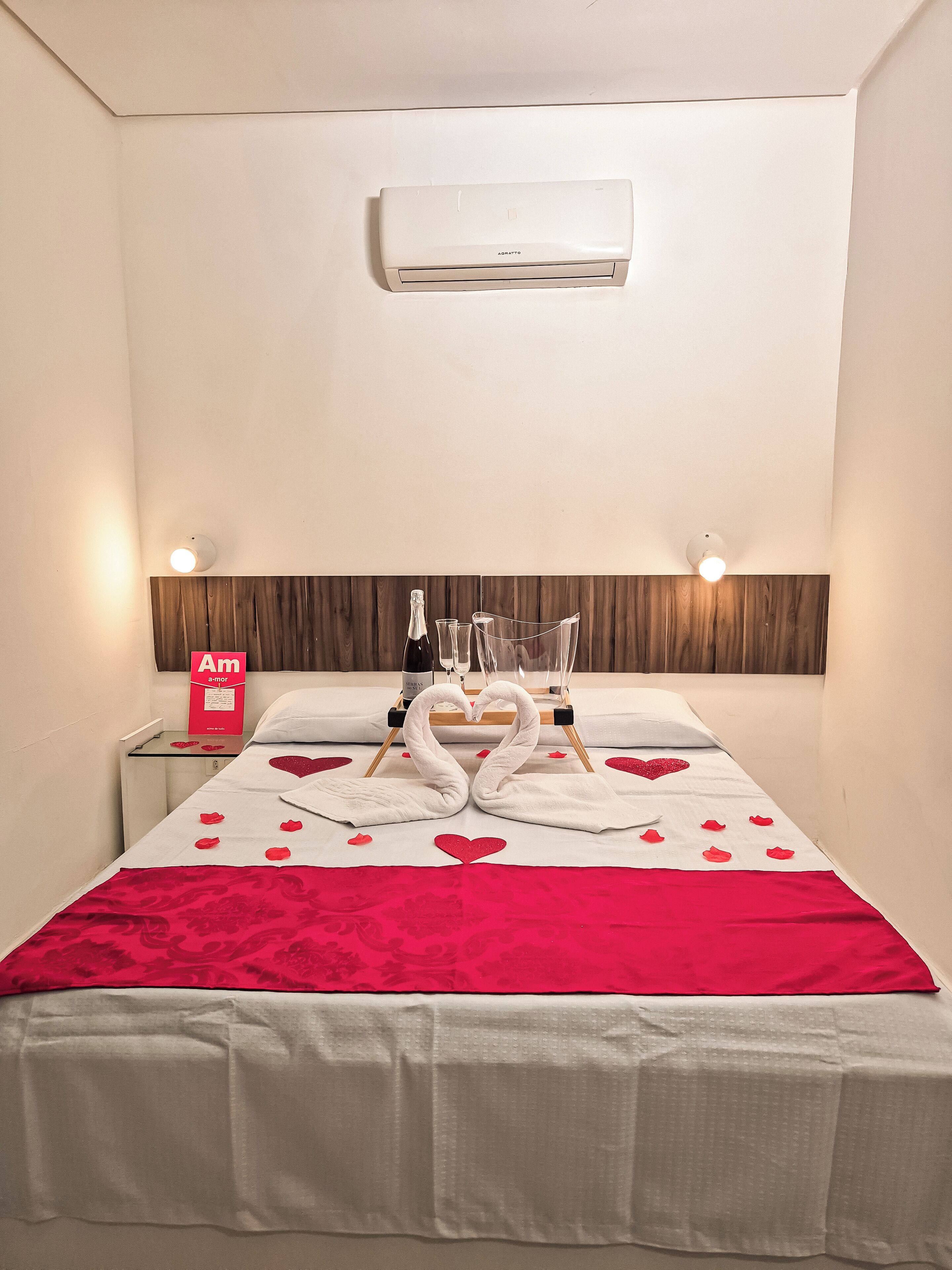 Habitación de hotel con cama, mesita de noche, aire acondicionado de pared y un adorno en la pared.