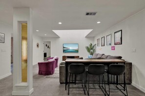 A modern interior with a bar area, seating, and artwork on the walls. - Walk to Whitewater Amphitheater-GameRoom & Firepit (Canyon Lake)