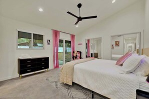 A bedroom with a bed, a dresser, a ceiling fan, and a window with curtains.