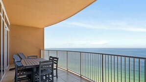 A balcony with a table and chairs, overlooking a clear view of the ocean. - Brand New Phoenix Gulf Tower 2507 /Lazy River/Beach
Your Vacation Getaway! (Orange Beach)