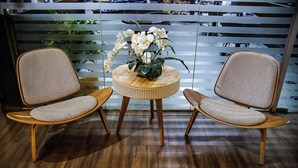 Two wicker chairs with patterned cushions, a small round table with a woven edge, and a potted orchid arrangement. - Hotel Graal Inn Uberaba (Uberaba)