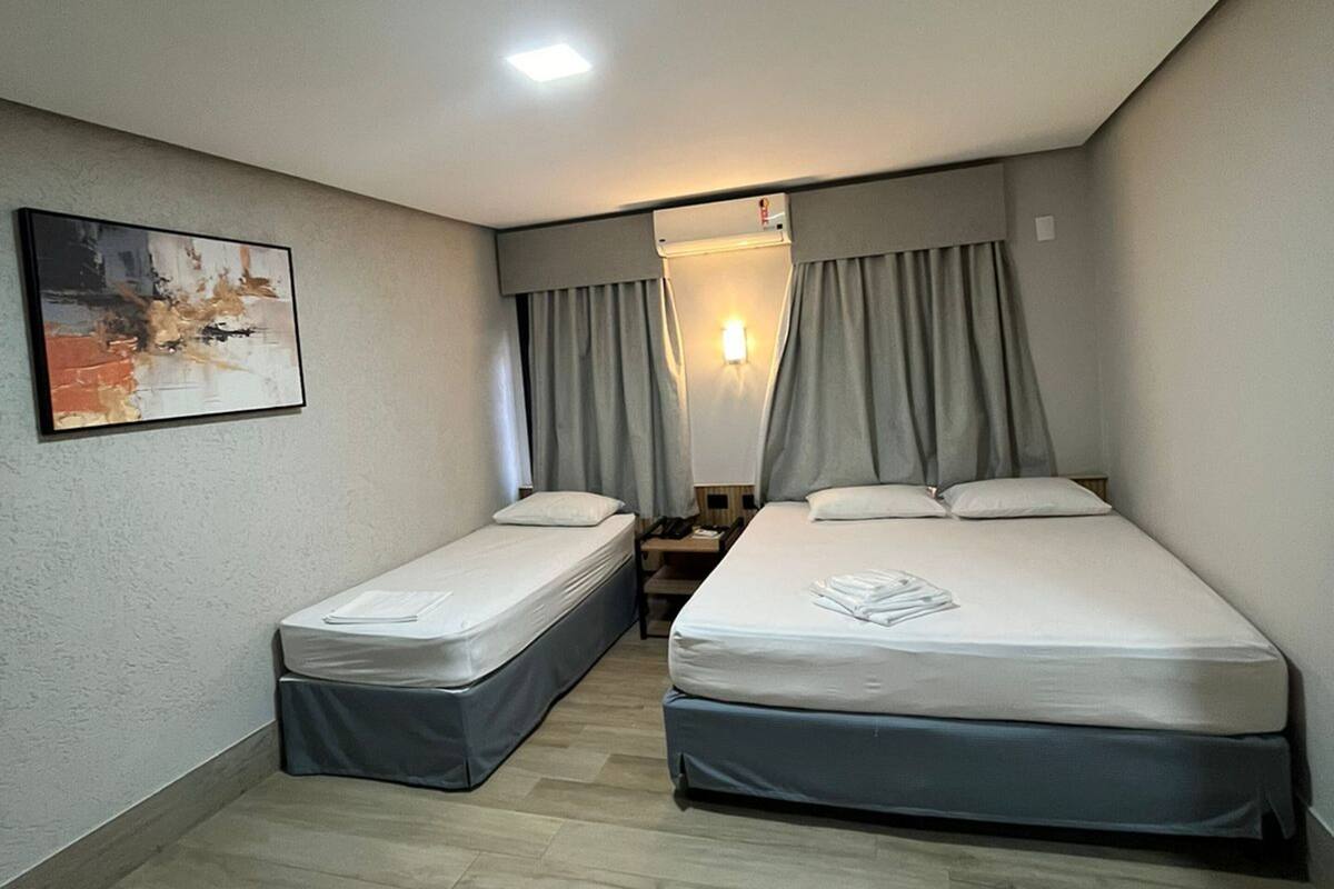 Une petite chambre moderne équipée de deux lits simples, d’un bureau et d’une chaise.