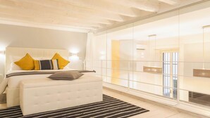 A modern bedroom with a large bed, a white bench, and a glass partition wall. - Heart Milan Apartments Duomo Missori (Milan)