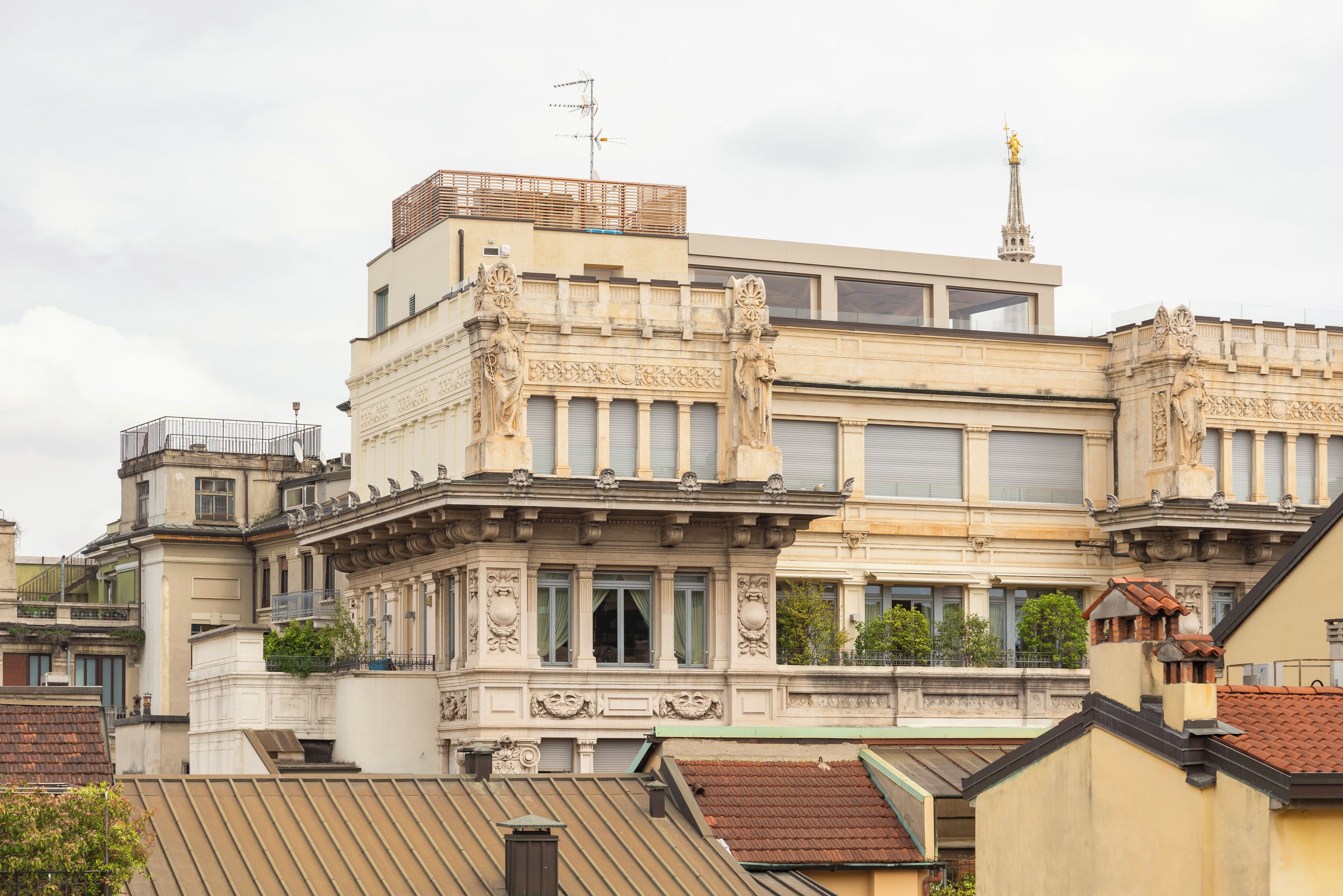 Un edificio de varios pisos con detalles arquitectónicos ornamentales, incluyendo estatuas y molduras decorativas.