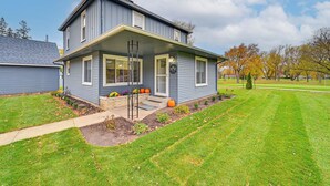 A two-story house with a front porch, a small garden with pumpkins, and a clear sky. - Home on Legacy Hills Golf Course w/ Patio! (LaPorte)